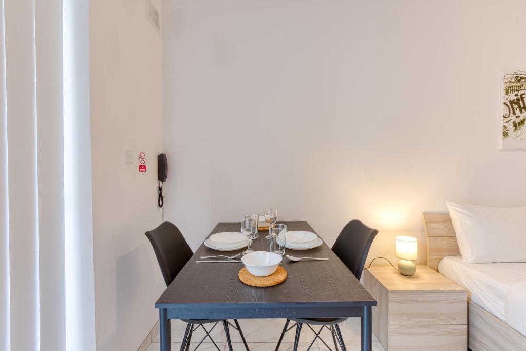 una sala da pranzo con tavolo, sedie e un letto di New Studio in Msida a Msida