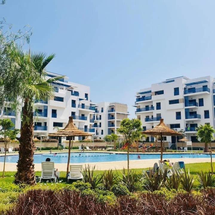 a swimming pool with chairs and umbrellas and buildings at Costamar Martil in Martil