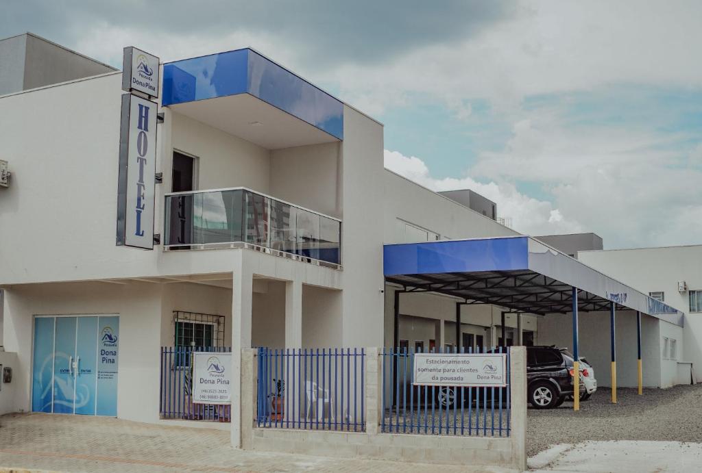 a large white building with a blue balcony at Hotel Dona Pina in Francisco Beltrão