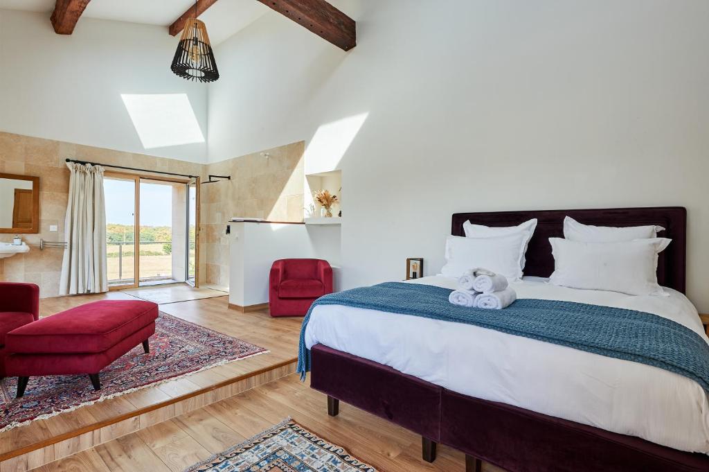 - une chambre avec un grand lit et une chaise rouge dans l'établissement Domaine de Badine, 15 min Bordeaux & Saint-Emilion, à Saint-Sulpice-et-Cameyrac