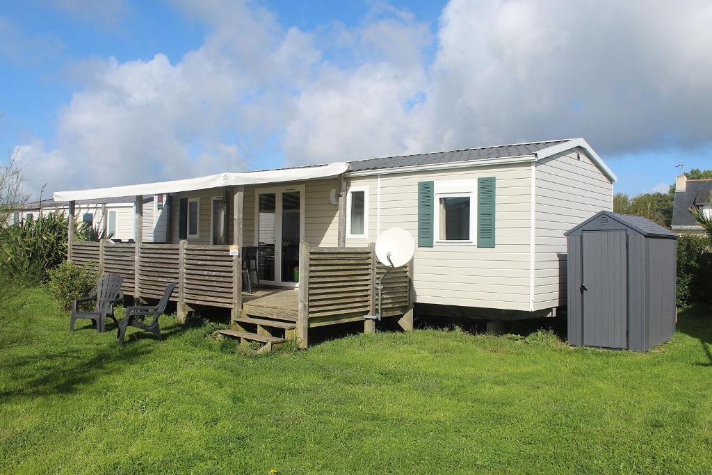 un mobile home blanc avec bancs dans un champ dans l'établissement Mobile-home 6 personnes dans camping avec piscine - accès direct plage - MADEN, à Sarzeau