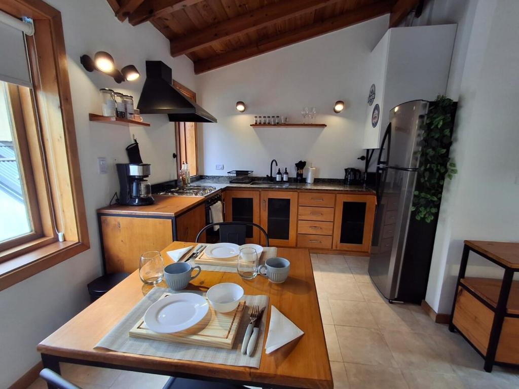 a kitchen with a wooden table with plates on it at Joli Apartments - Studio 12 in San Martín de los Andes