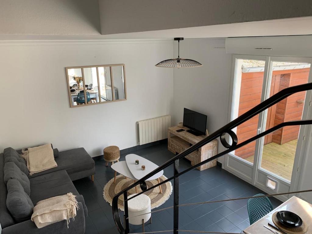 a living room with a couch and a tv at Hébergement Guer in Guer