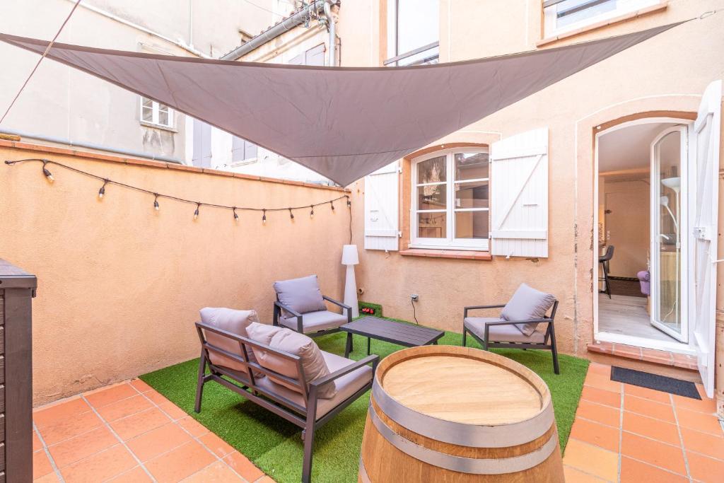 d'une terrasse avec des chaises, une table et un tonneau. dans l'établissement Le cocon Toulousain, à Toulouse