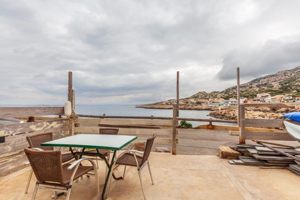 un patio avec une table et des chaises et l'océan dans l'établissement I Feel Goudes, à Marseille