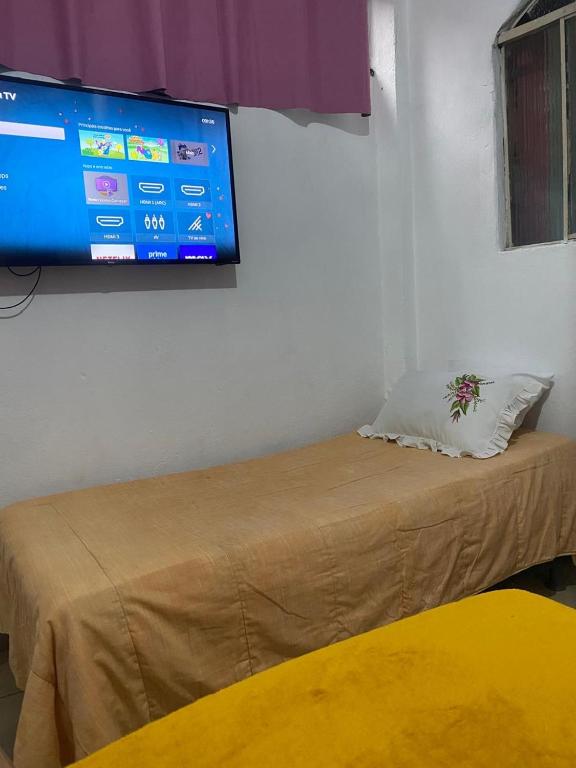 un lit dans une chambre avec une télévision au mur dans l'établissement Kitnet Diamantina, à Diamantina