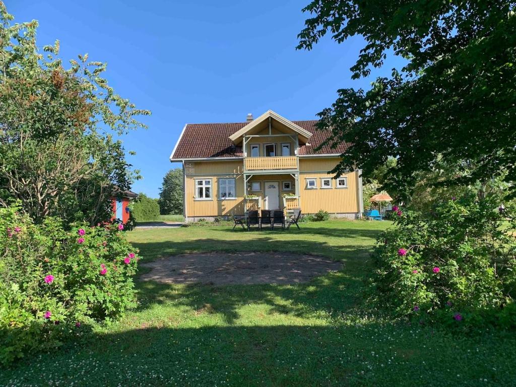 a large yellow house with a yard with flowers at Stort hus på Fen i Ulefoss i rolige omgivelser in Ulefoss