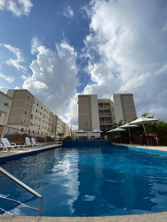 a pool at a hotel with chairs and buildings at Apartamento Praia de Ponta com dois quartos in Natal
