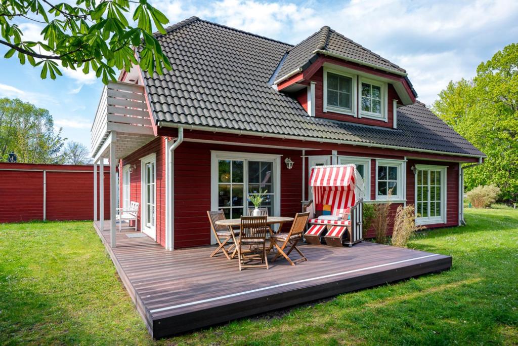 a red house with a deck with a table and chairs at Sandsturm in Prerow