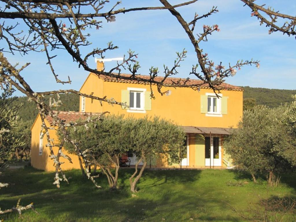 une maison jaune avec des arbres devant elle dans l'établissement Superbe villa entourée d'oliviers proche du village d'Aups - FR-1-822-7, à Aups