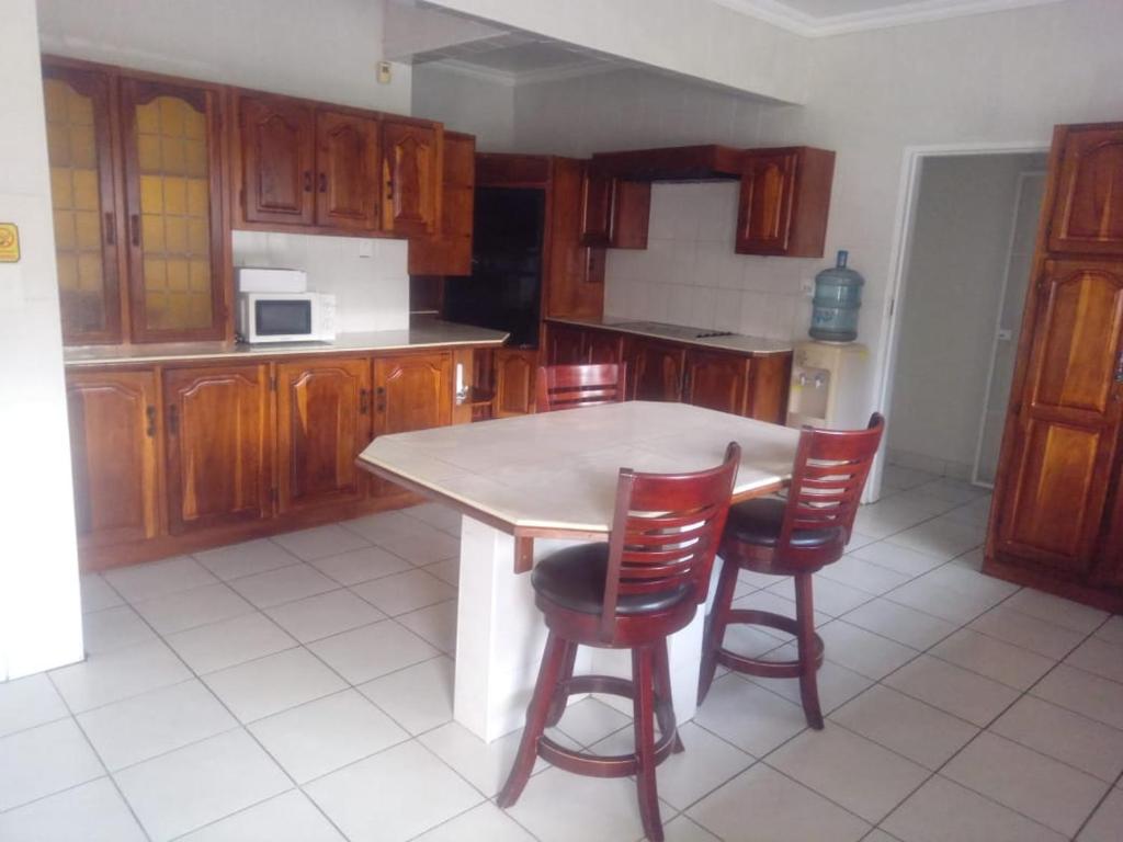 a kitchen with wooden cabinets and a table and chairs at Simekhona Guest House in Aangewysd