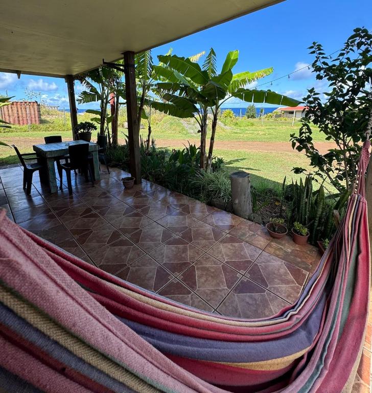 a hammock on a patio with a table and a field at Manu Kehu in Hanga Roa