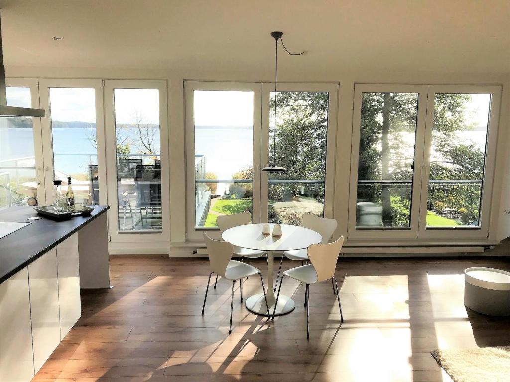 a kitchen with a white table and chairs and windows at Ferienwohnung Seepanorama in Groß Wittensee