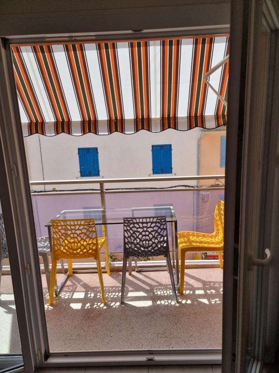 3 chaises et une table à l'extérieur d'une fenêtre dans l'établissement BANDOL T2 HYPER CENTRE rue calme, à Bandol