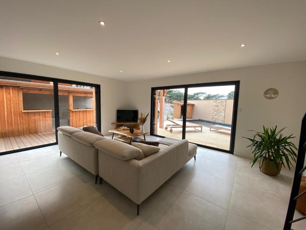 un ampio soggiorno con divano e patio di Comfortable holiday villa with spa a Lacanau