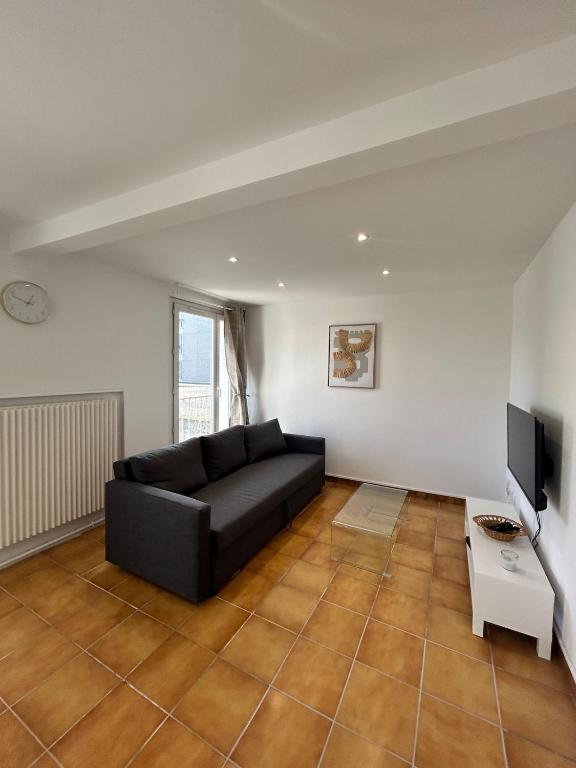 un salon avec un canapé noir et une télévision dans l'établissement Le Chambéry 6p parking privé clim, à Toulouse