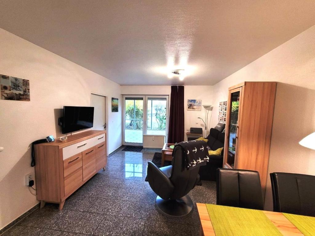 a living room with a television and a desk with a chair at Kleine Auszeit in Dorum-Neufeld