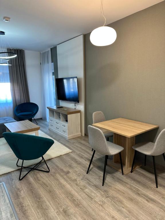 a living room with a table and chairs and a tv at Apartmens MAMA in Sombor