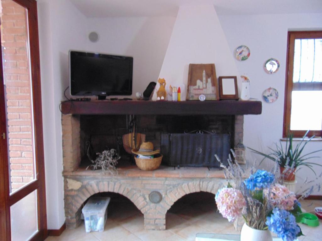 a living room with a fireplace with a flat screen tv at Podere Luma Camera Melograno in Gambassi Terme