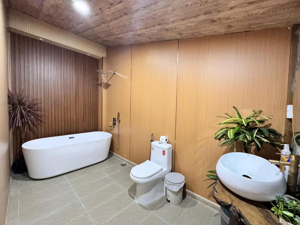 a bathroom with a tub and a toilet and a sink at Lá Garden Homestay in Long Xuyên