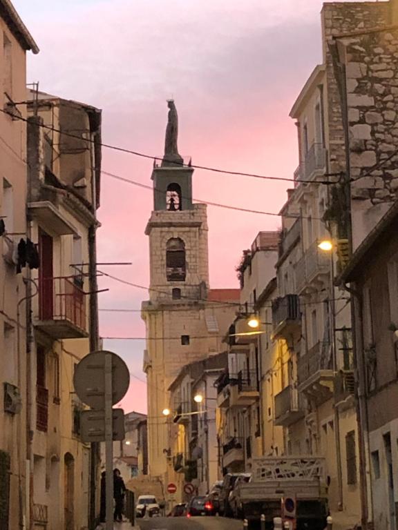 un bâtiment avec une tour d'horloge au milieu d'une rue dans l'établissement Joli petit appartement dans le quartier haut, à Sète