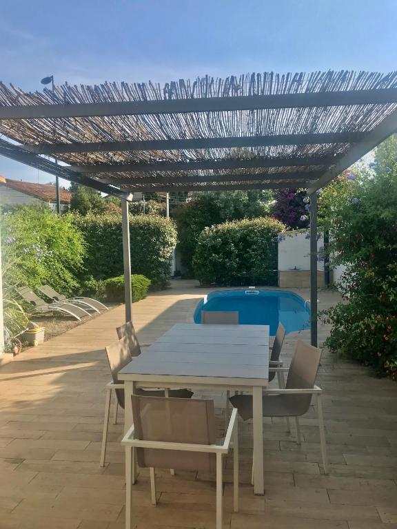 une table et des chaises blanches sous une pergola dans l'établissement Sete Villa Le Gabanon piscine et 1ere etang, à Sète