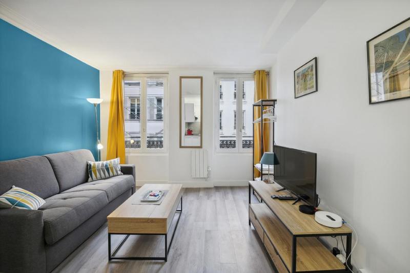 un salon avec un canapé et une télévision dans l'établissement 513 Suite Marie - Superbe logement Quartier Marais, à Paris