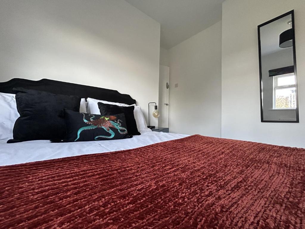 a bedroom with a large bed with a red blanket at The Cotswold Cornerstone in Billingham