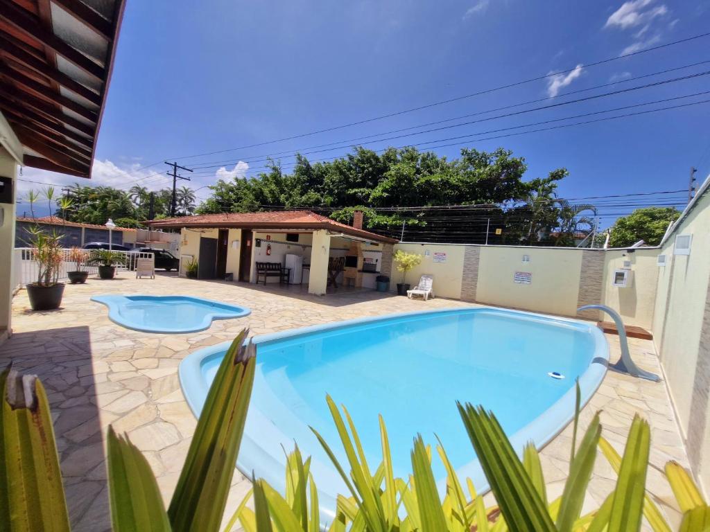ein Swimmingpool in einem Hof mit einem Haus in der Unterkunft Apartamento completo Condomínio Caribe Ubatuba in Ubatuba