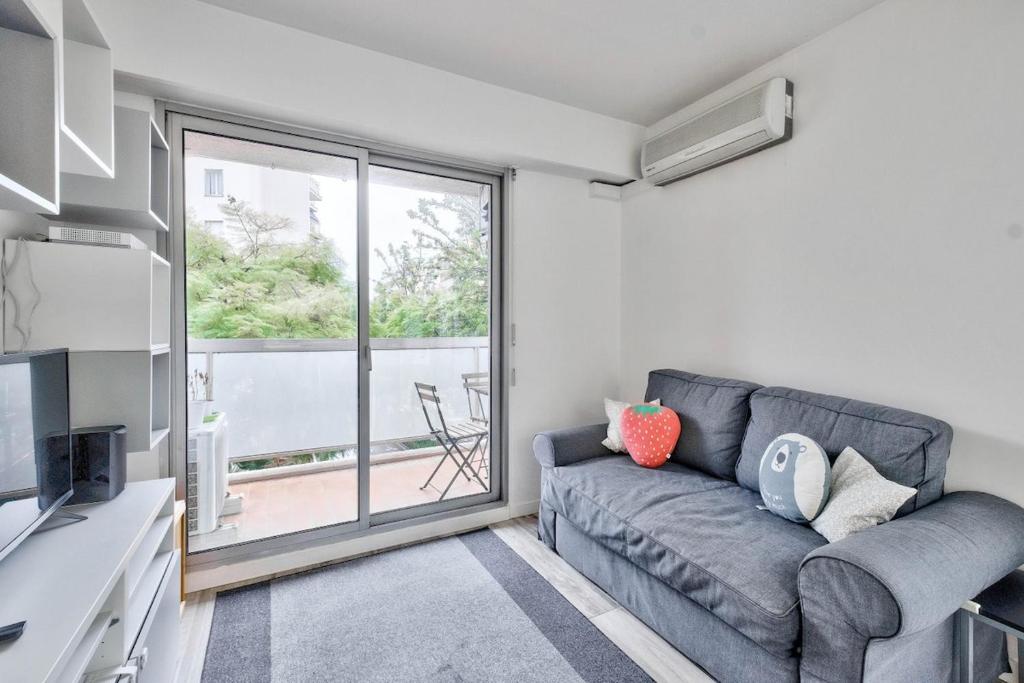 un salon avec un canapé et une grande fenêtre dans l'établissement Flat with balcony 15min from Promenade des Anglais, à Nice