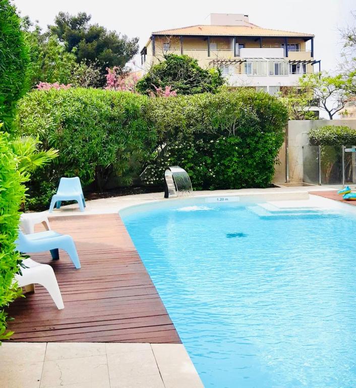 une piscine avec deux chaises et une maison dans l'établissement Beau Studio Prado Plage Parc Piscine Stade, à Marseille