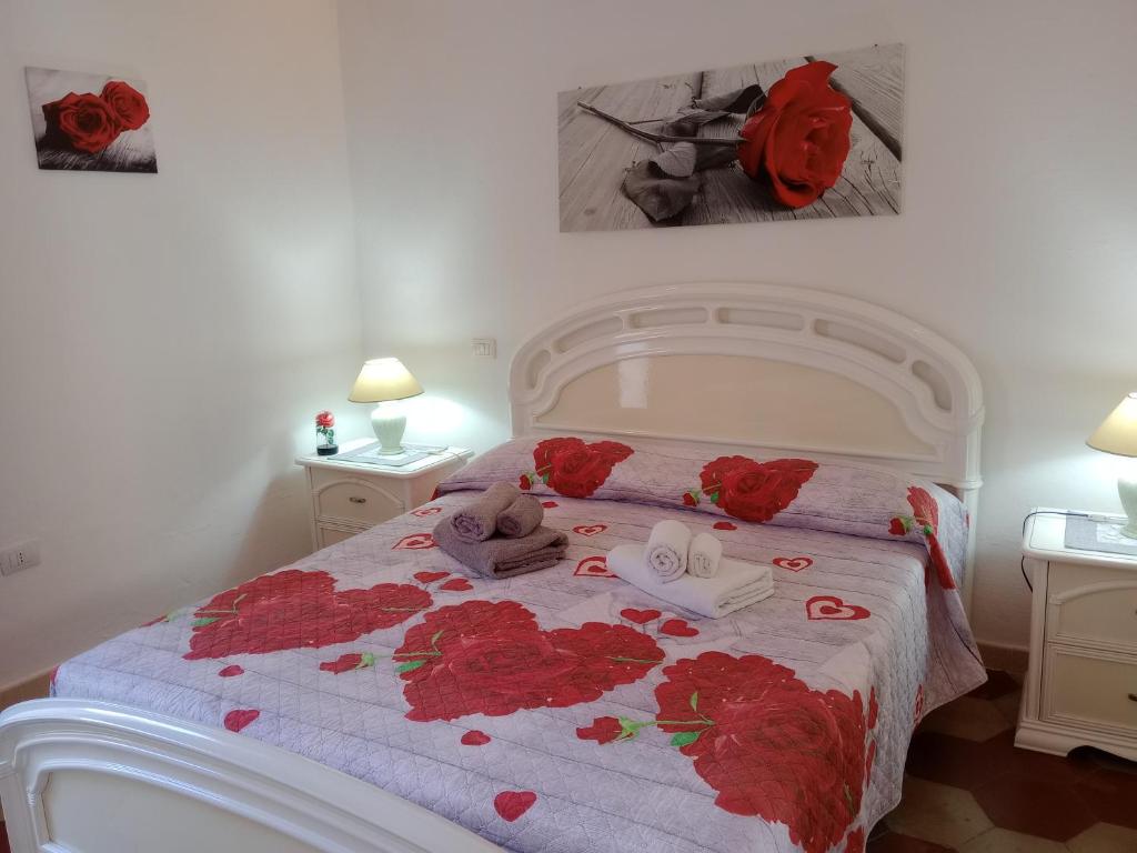 a bedroom with a bed with red roses on it at Appartamento vacanze Le rose in Bosa
