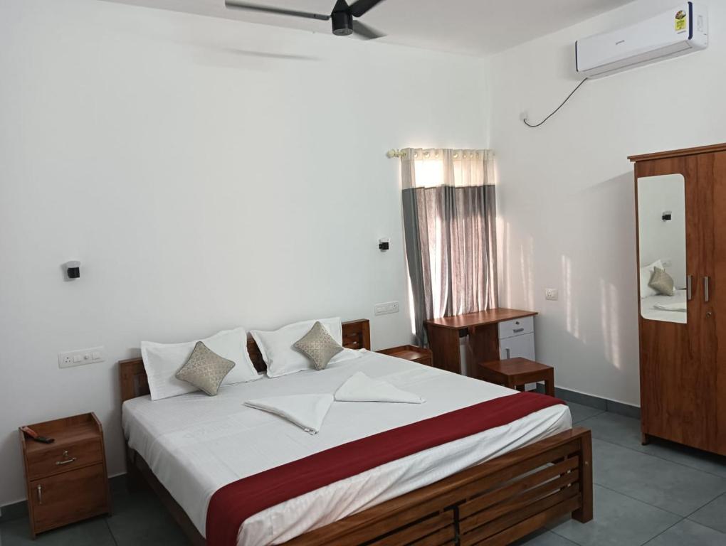 una camera da letto con un grande letto con lenzuola bianche di Captain's Castle a Pallipuram