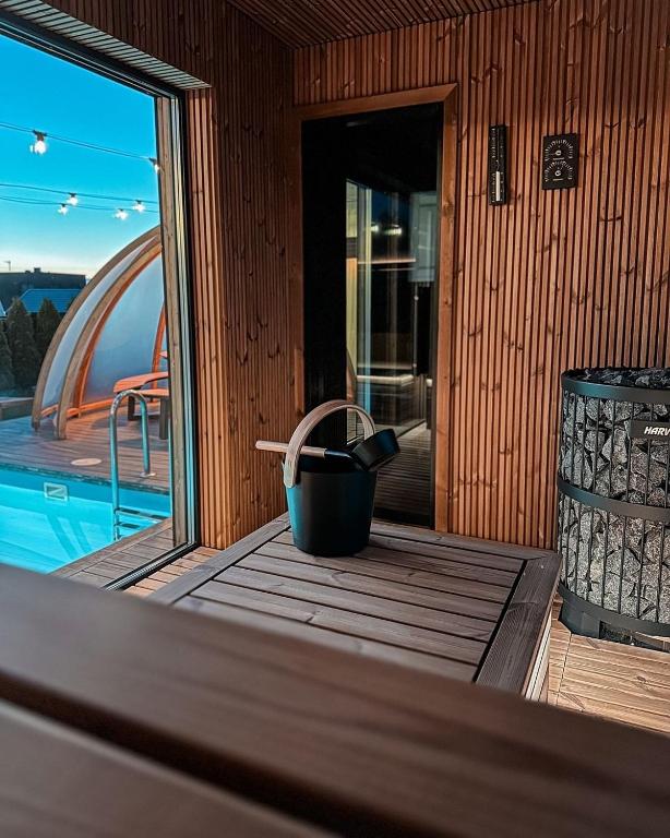 a wooden porch with a trash can and a pool at Išskirtinis namas Palangoje! in Palanga