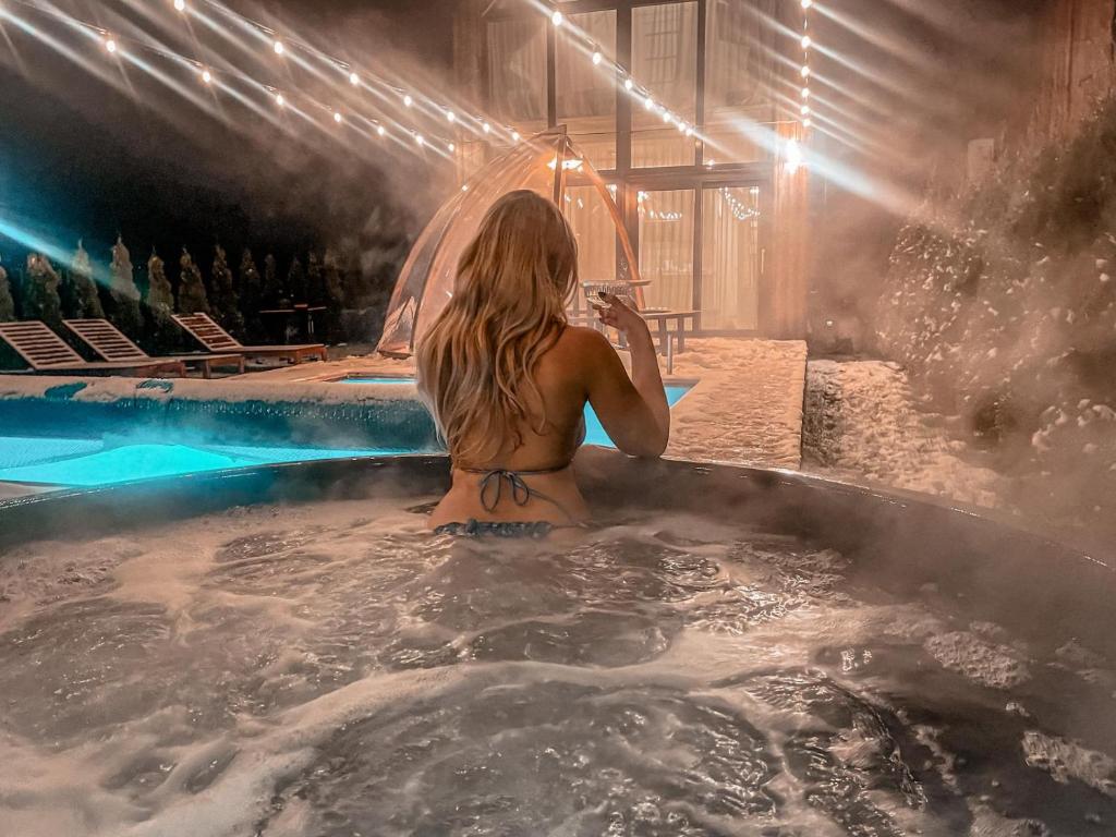 a woman sitting in a hot tub in a swimming pool at Išskirtinis namas Palangoje! in Palanga