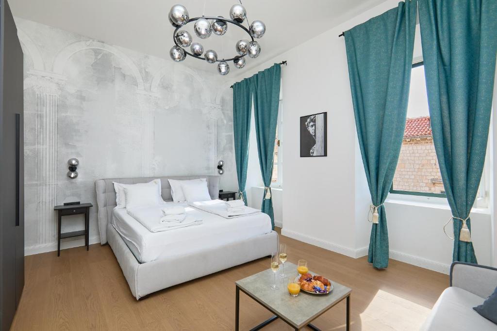a bedroom with a white bed and a chandelier at TUDISI LUX SUITES by DOMINIUM in Dubrovnik