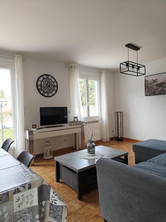 a living room with a couch and a tv at Maison 6 pers, avec jardin, clim et pétanque in Thuir