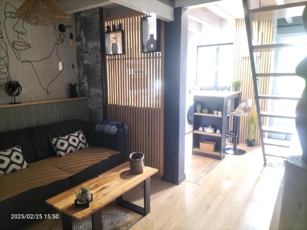 een woonkamer met een bank en een tafel bij Au bord du vieux Moulin - près de Bordeaux in Mérignac