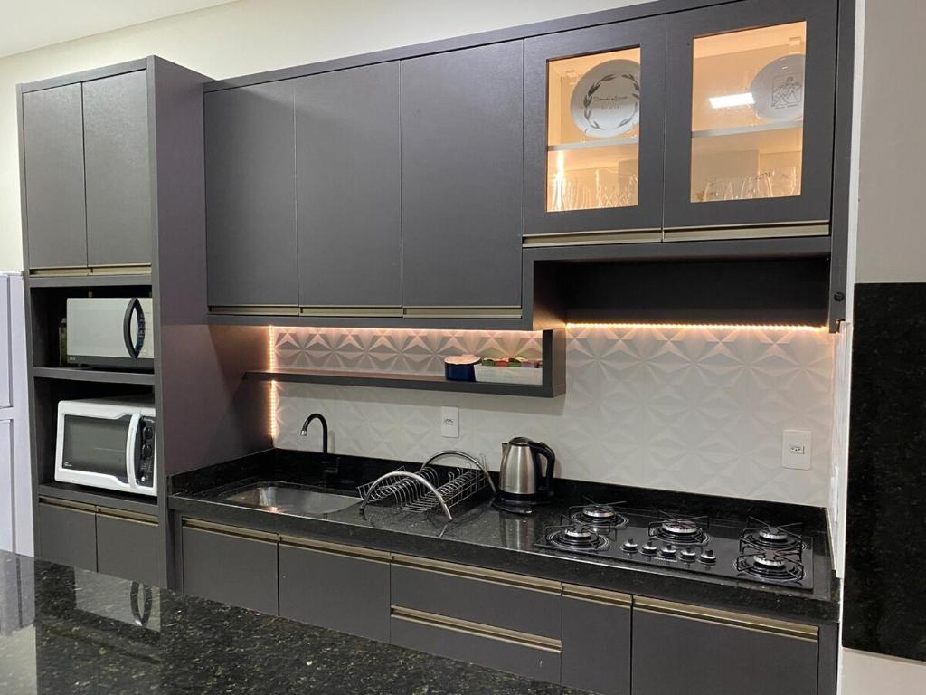 eine Küche mit einer Spüle, einem Herd und Schränken in der Unterkunft Casa na praia in Xangri-lá