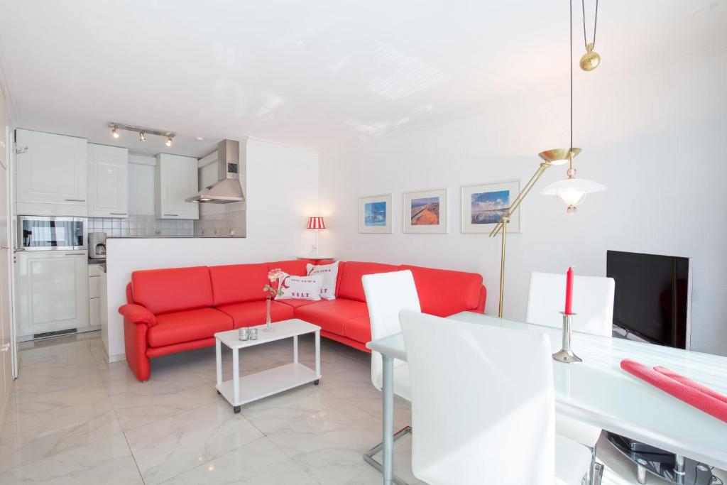 a living room with a red couch and a kitchen at Windeby 7T in Wenningstedt