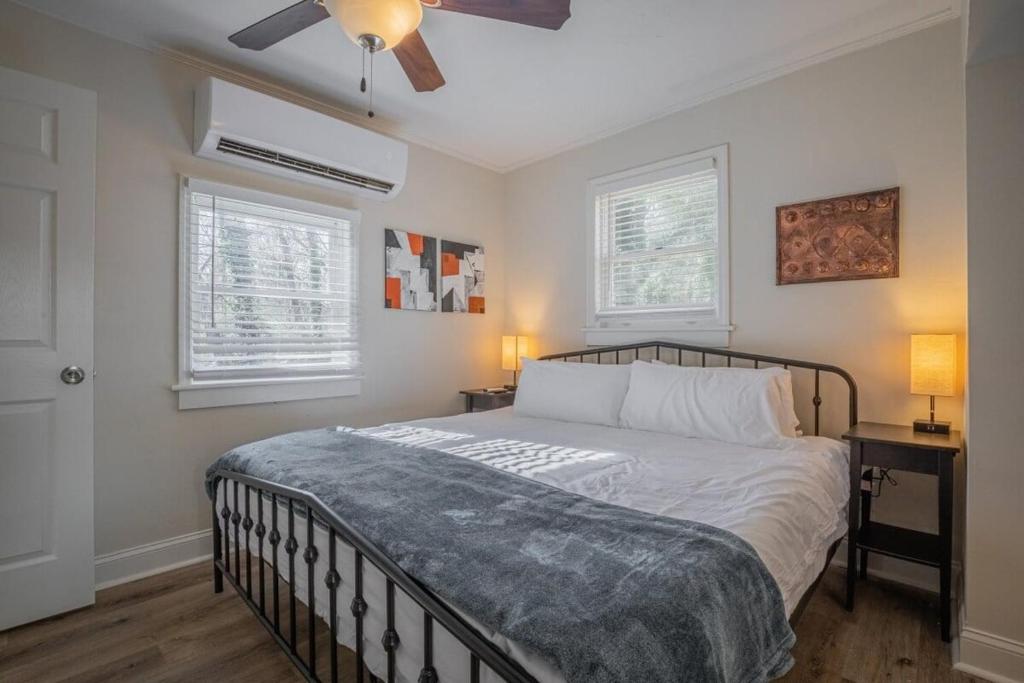 ein Schlafzimmer mit einem Bett mit zwei Nachttischen und zwei Fenstern in der Unterkunft Cara's Cottage in Athens