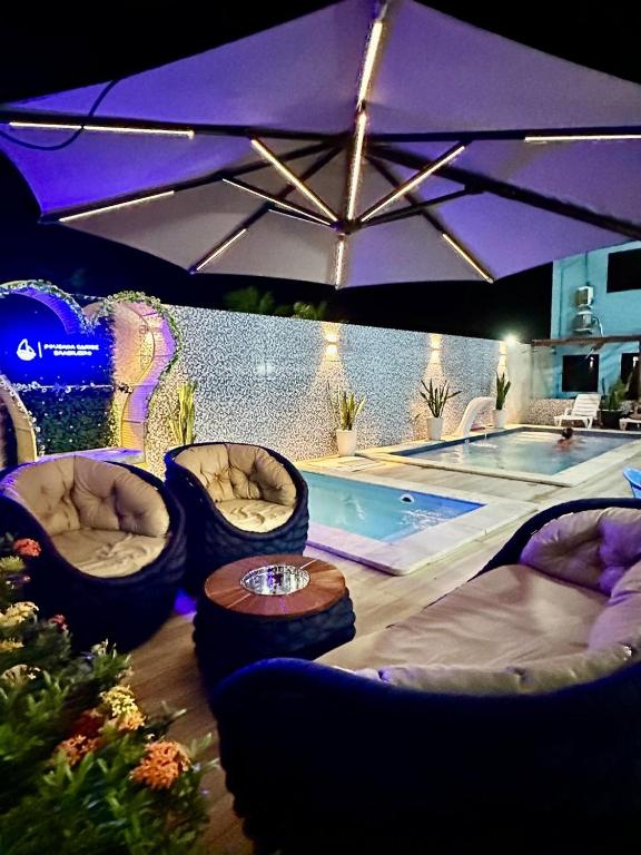 a swimming pool with chairs and a table and an umbrella at Pousada Caribe Brasileiro in Maragogi