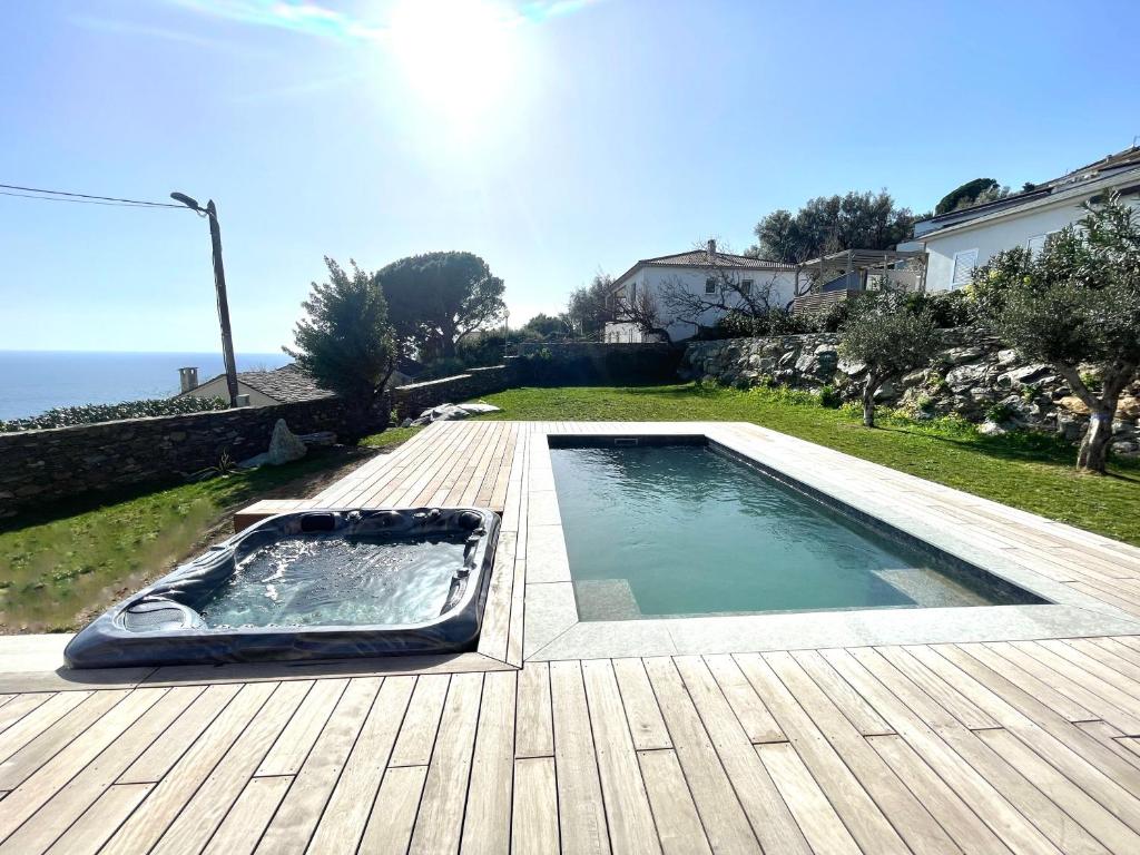 - une piscine sur une terrasse en bois à côté de l'océan dans l'établissement Magnifique Villa Neuve Cap Corse, à Brando