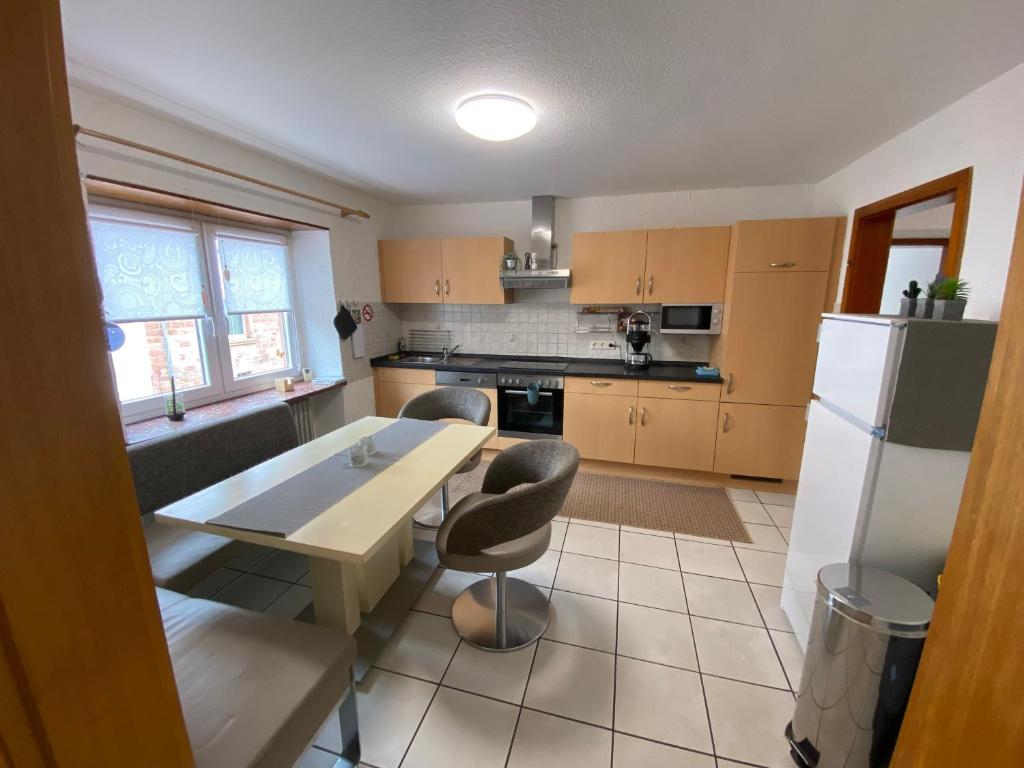une cuisine avec une table, des chaises et un réfrigérateur dans l'établissement Apartment und Ferienwohnung Mackenbach 2, à Mackenbach