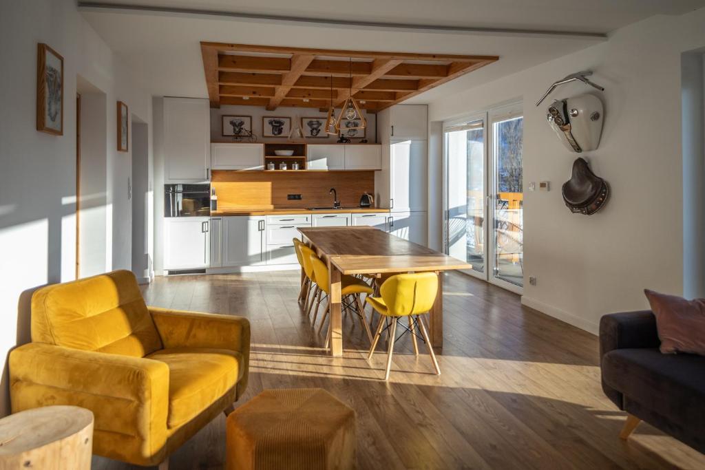 Una sala de estar con una mesa de madera y sillas amarillas. en HARLEY FAMILY APARTAMENT, en Muszyna