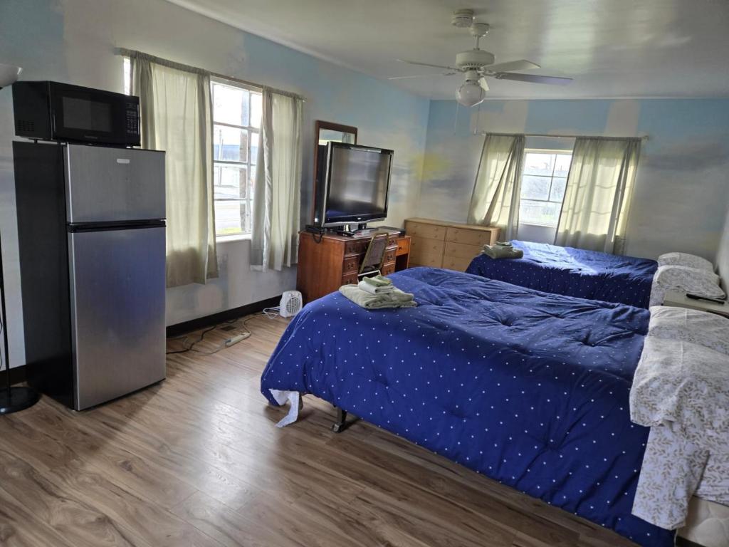a bedroom with two beds and a refrigerator and a television at Mountaineer Motel in Mount Storm