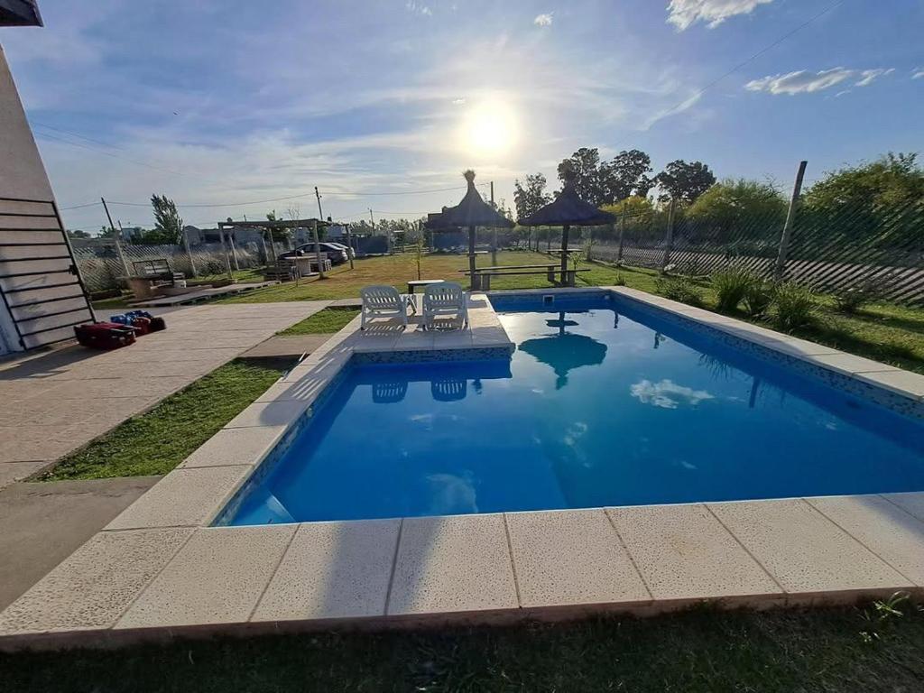 a swimming pool with two chairs and a table at Quinta La Deseada Brandsen in Estación Coronel Brandsen