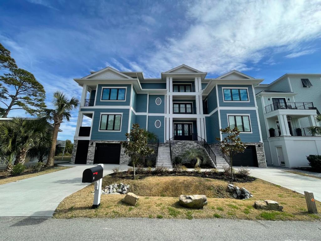 a large blue house with a garden in front of it at 8 Sea Front, Oceanfront Estate, Pool, Game Room, Elevator in Hilton Head Island