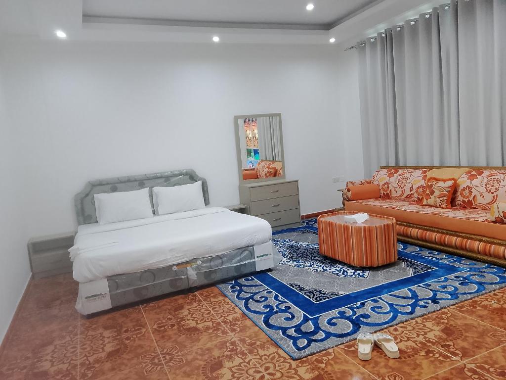 Green Resort Hotel AL khaburah في As Sarhāt: غرفة نوم بها سرير وأريكة