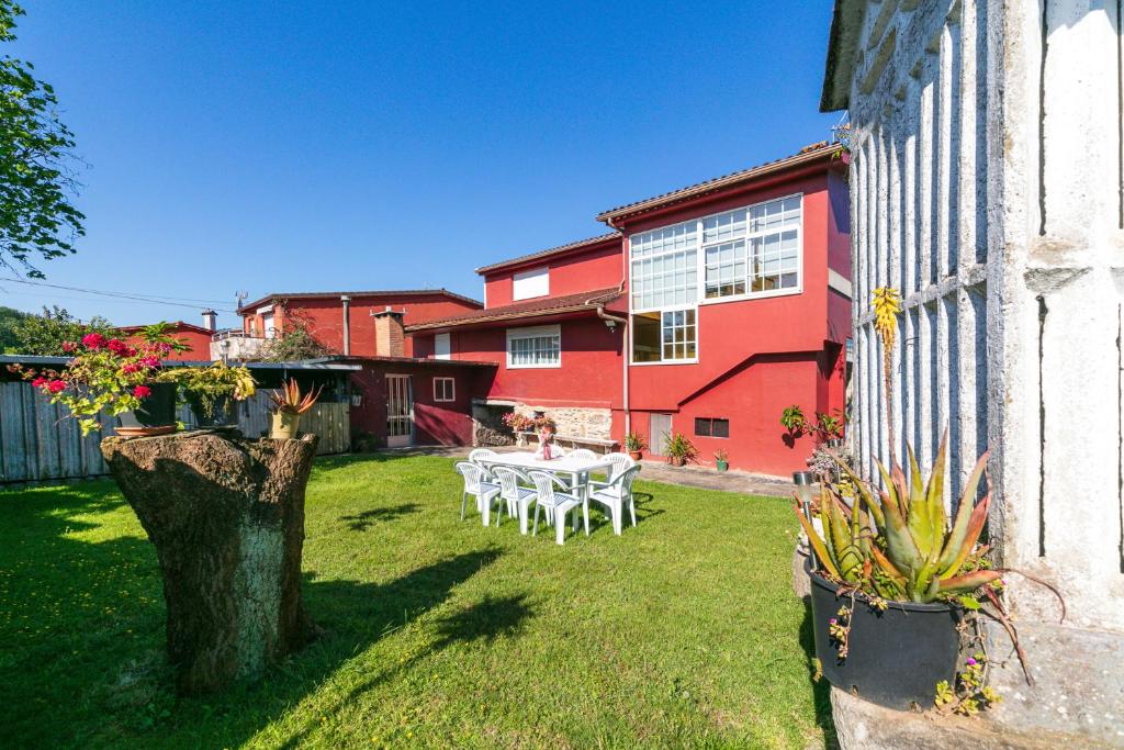 Un patio con una mesa blanca y un edificio rojo. en Retiro rural con parking by CABANA Rentals, en Vigo